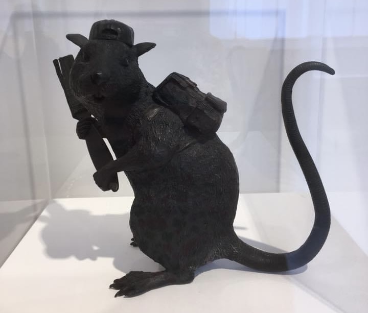 A Banksy rat sculpture in its display case.