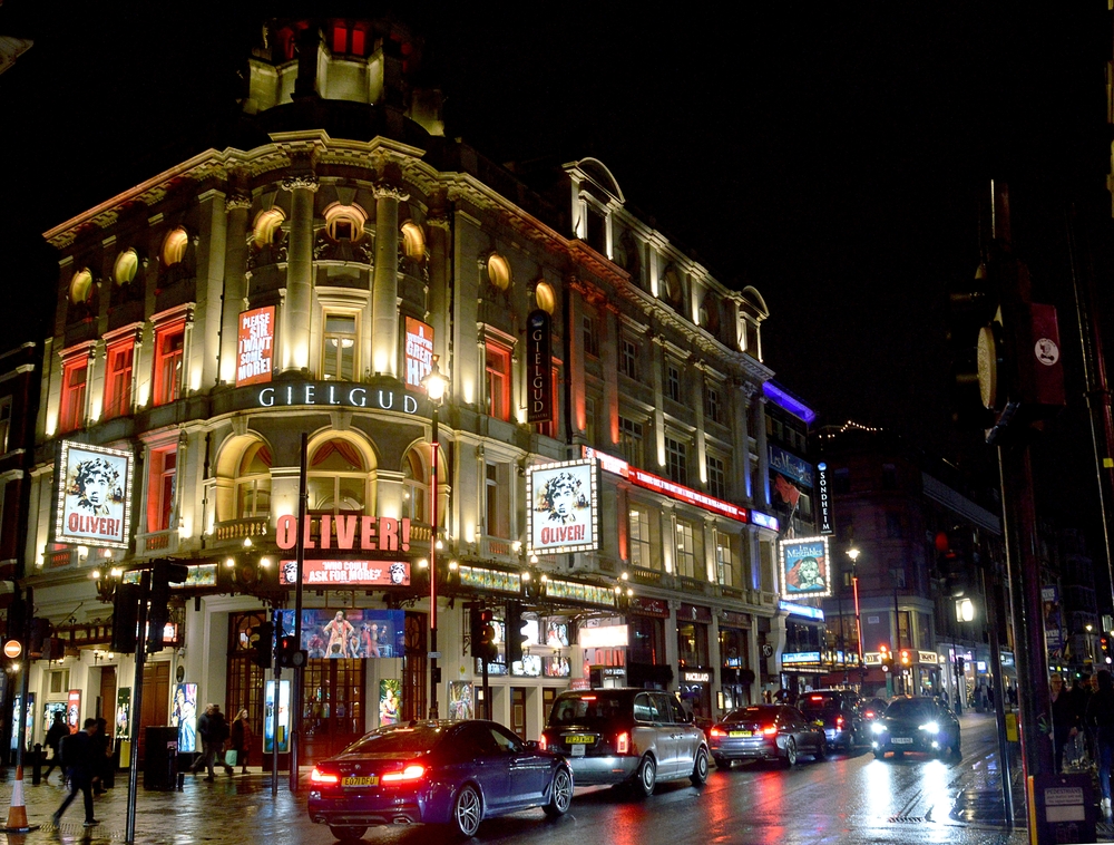 The exterior of the Gielgud Theatre in London at nighttime, with passing traffic.